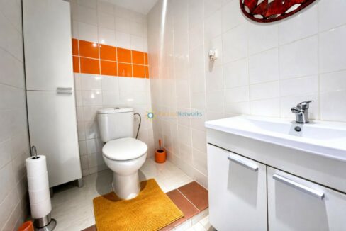 Baño moderno y luminoso con detalles naranjas