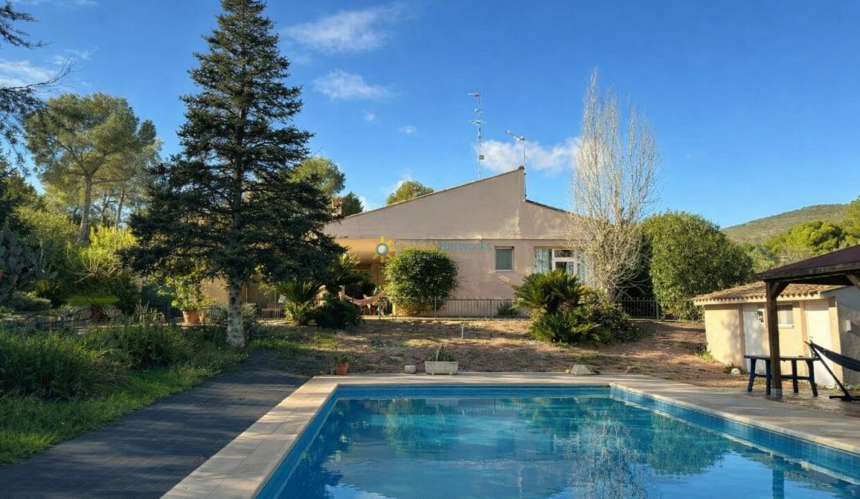 Casa mediterránea con piscina en paisaje verde