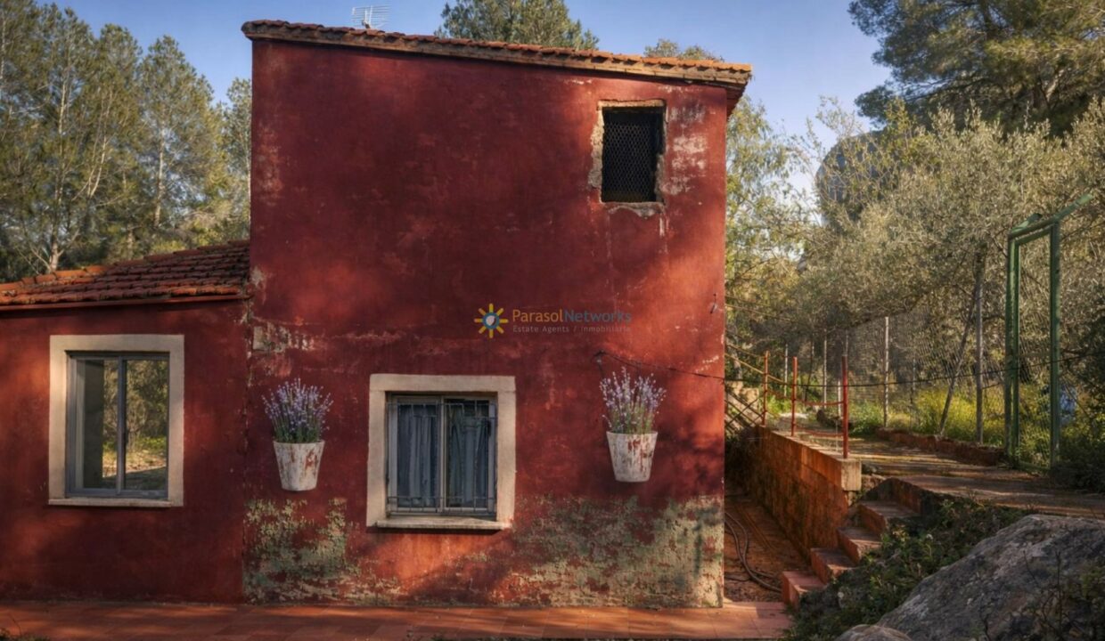 Casa roja entre árboles y sol