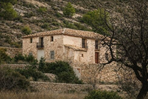Casa rural envejecida en paisaje rocoso
