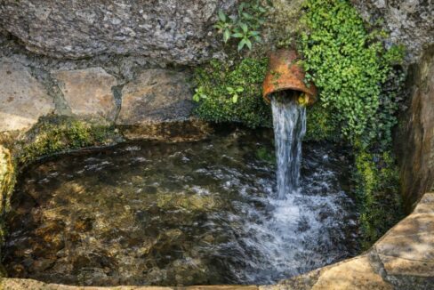 Fuente de agua antigua en paisaje rocoso