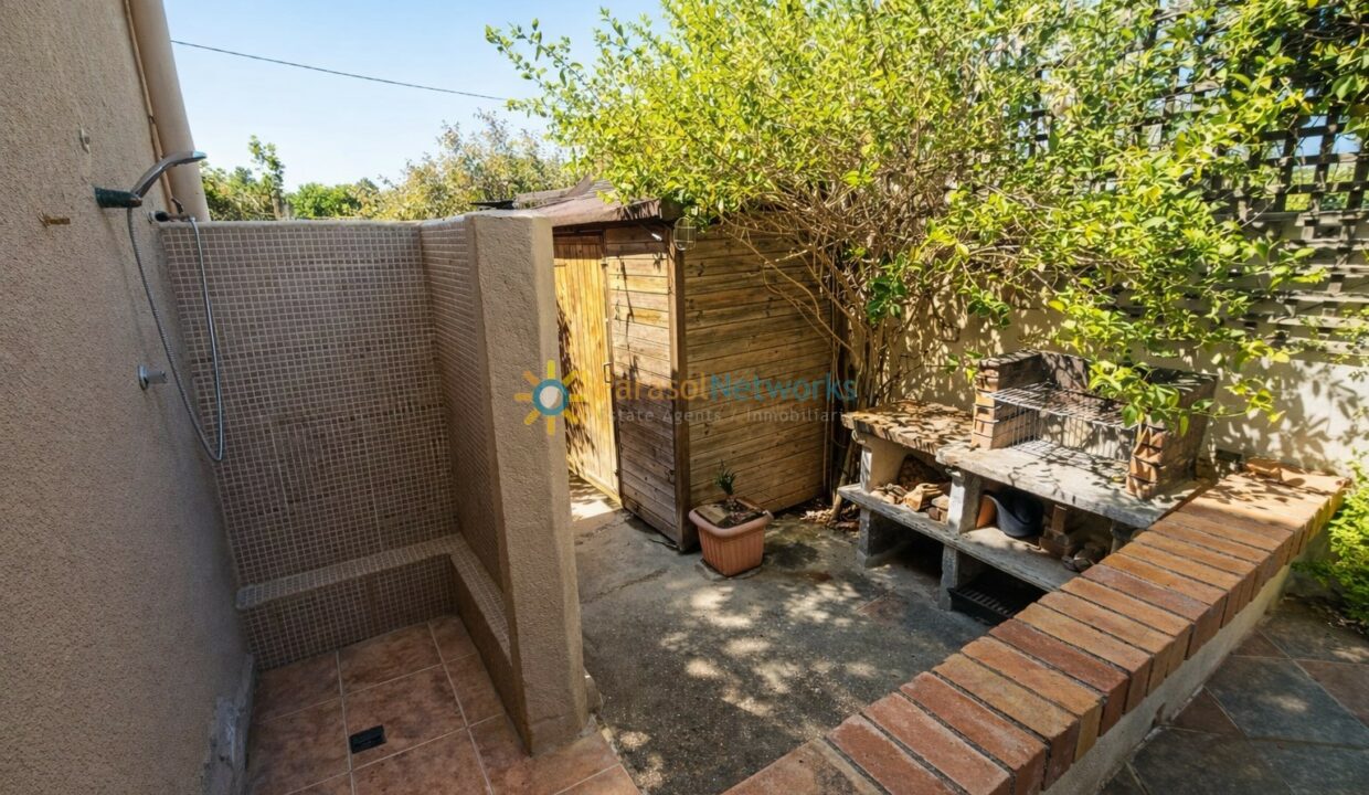 Jardín soleado con ducha exterior