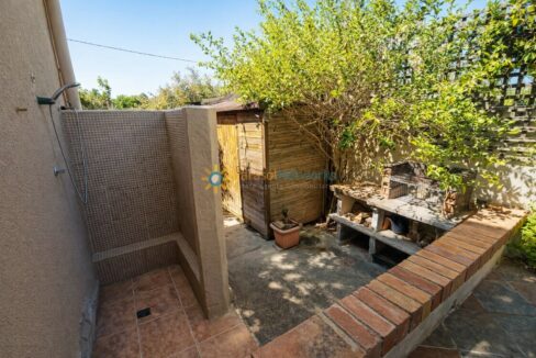 Jardín soleado con ducha exterior