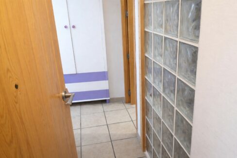 Pasillo con puerta de madera y cabina violeta