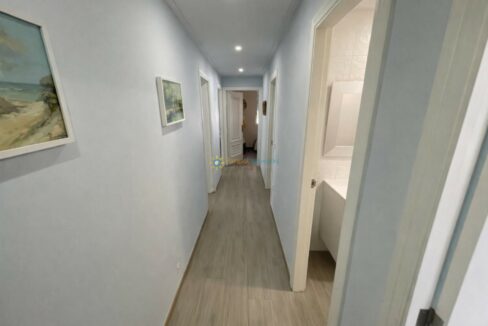 Pasillo luminoso con cuadros y baño