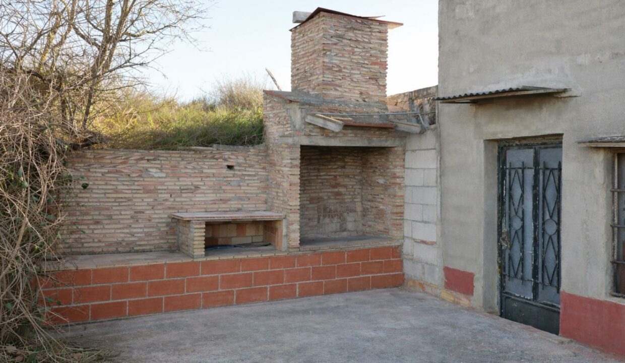 Patio con barbacoa rústica y antiguo edificio
