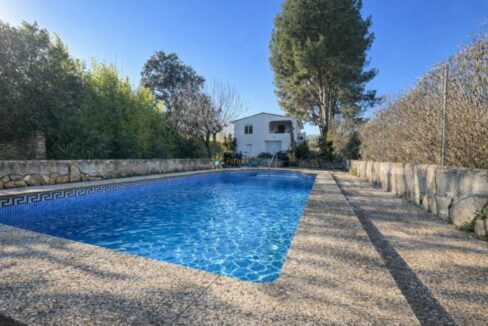 Piscina al sol con casa blanca