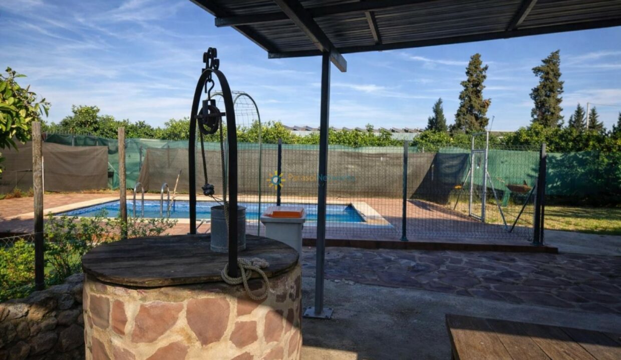 Pozo de piedra y piscina al fondo