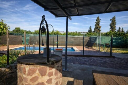 Pozo de piedra y piscina al fondo